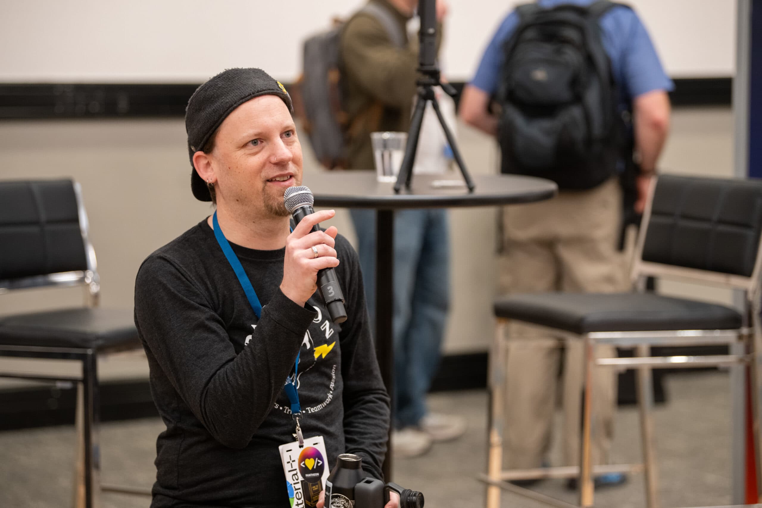 Chris Reynolds holding and speaking into a microphone from a seated position taken at DrupalCon Atlanta 2025